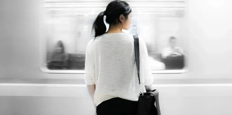 白いセーターを着て前を向いて歩く女性の後ろ姿